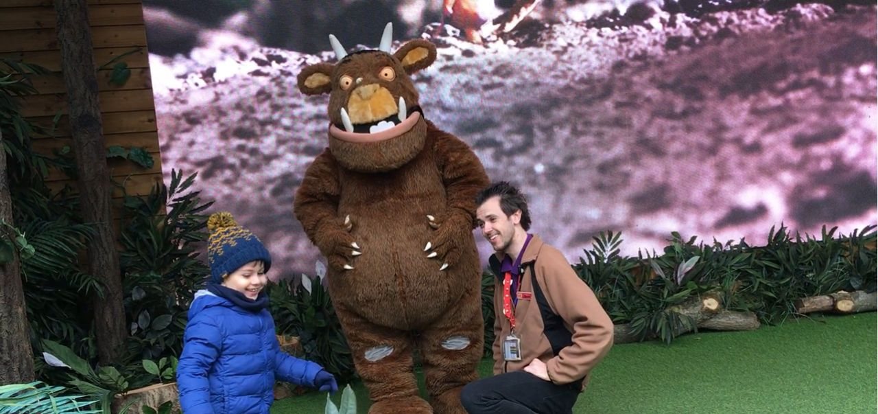 Young Lucca laughing as he meets the Gruffalo at Chessington World of Adventures, with a member of staff