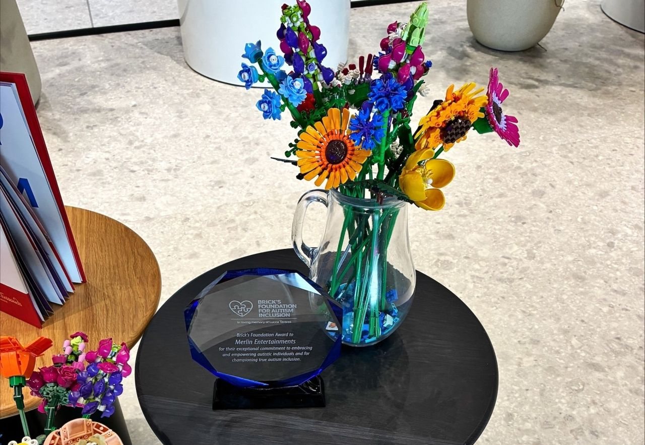 The Brick's Foundation Award to Merlin Entertainments, beside a vase of flowers made from LEGO bricks