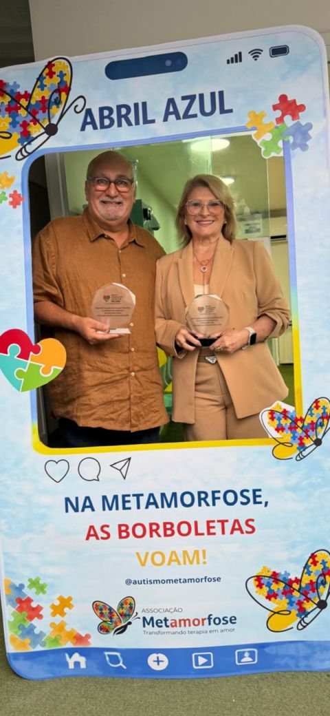 Roberto Moura and Sandra Cerqueira Moura holding their awards in a Blue April (Abril Azul) photo frame at Associação Metamorfose