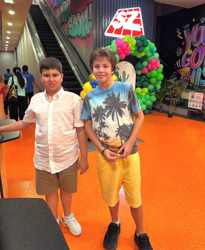 Lucca and Umberto standing together by a colourful balloon arch
