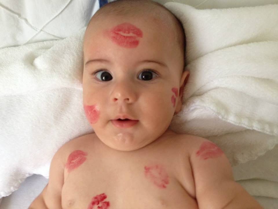 Baby Lucca lying on a white towel, covered in red lipstick kisses
