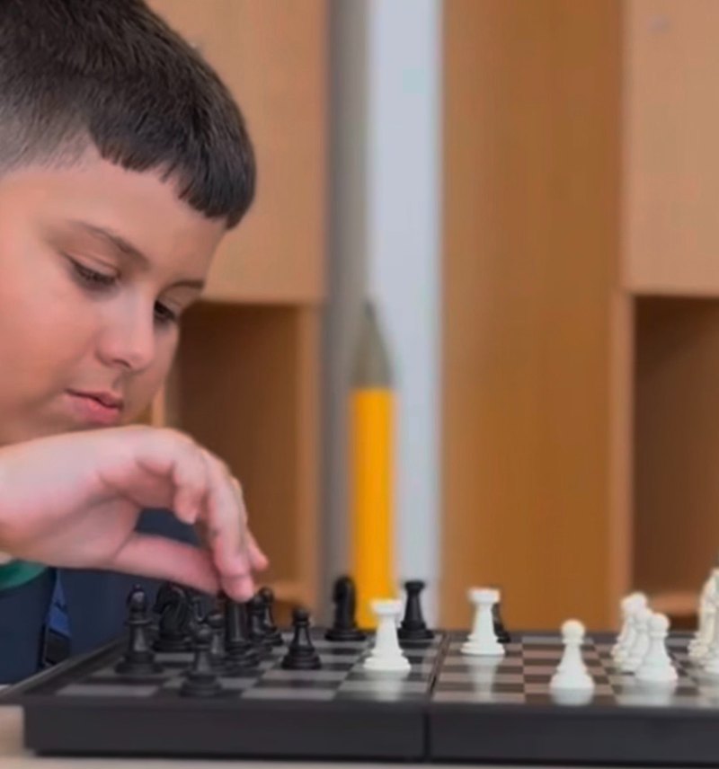 Lucca concentrating as he moves a chess piece